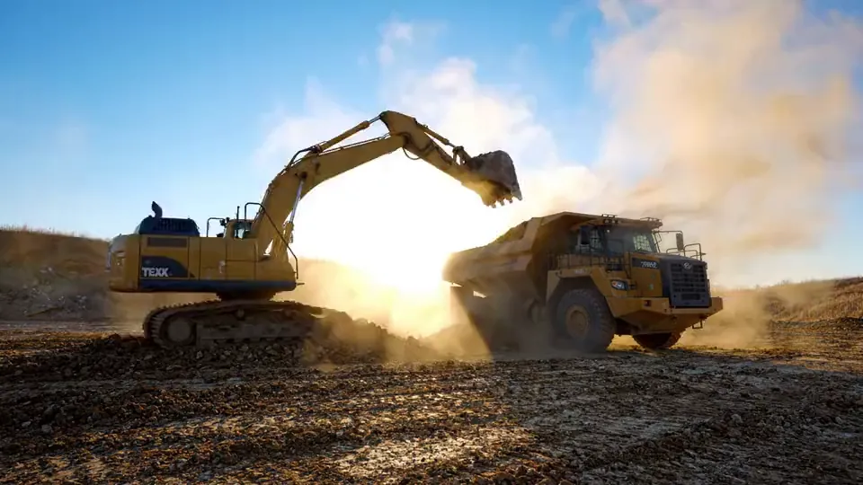 Tracked excavator loading an articulated haul truck on a cut and fill operation