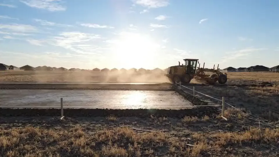 Motor grader cutting a building pad to grade with string line set