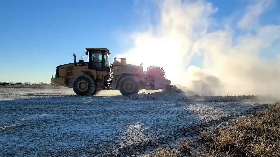 Wheel loader working lime into subgrade in a cloud of dust